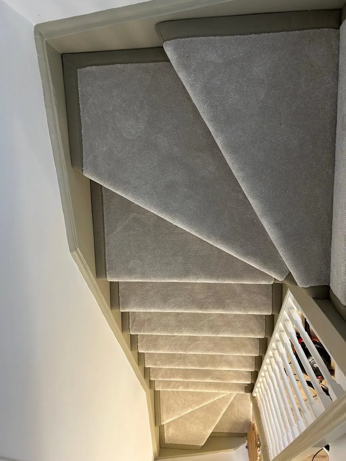 Grey stair carpet with bound edges fitted on winding stairs, North London