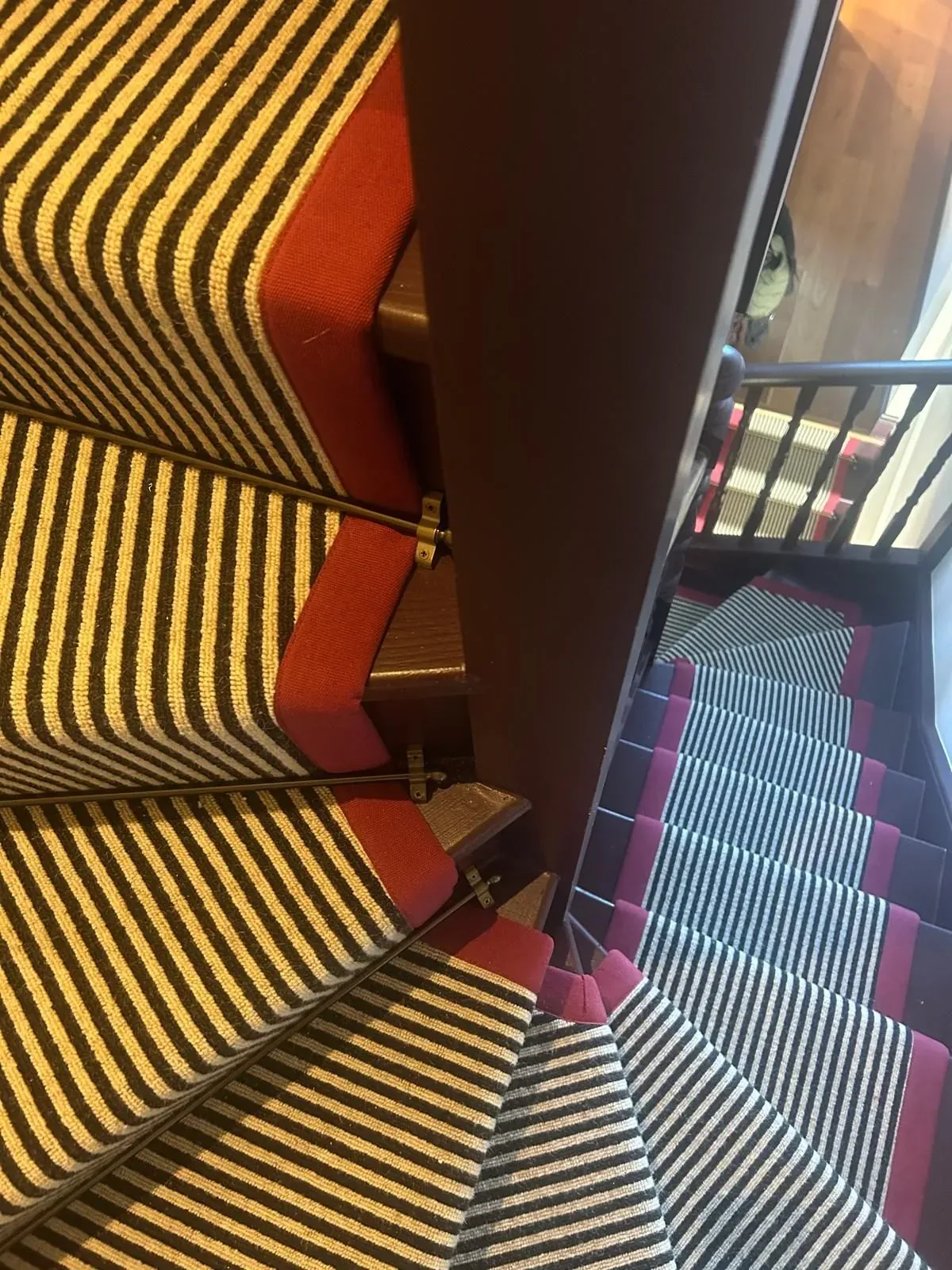 Striped stair runners with red borders and stair rods on a period staircase