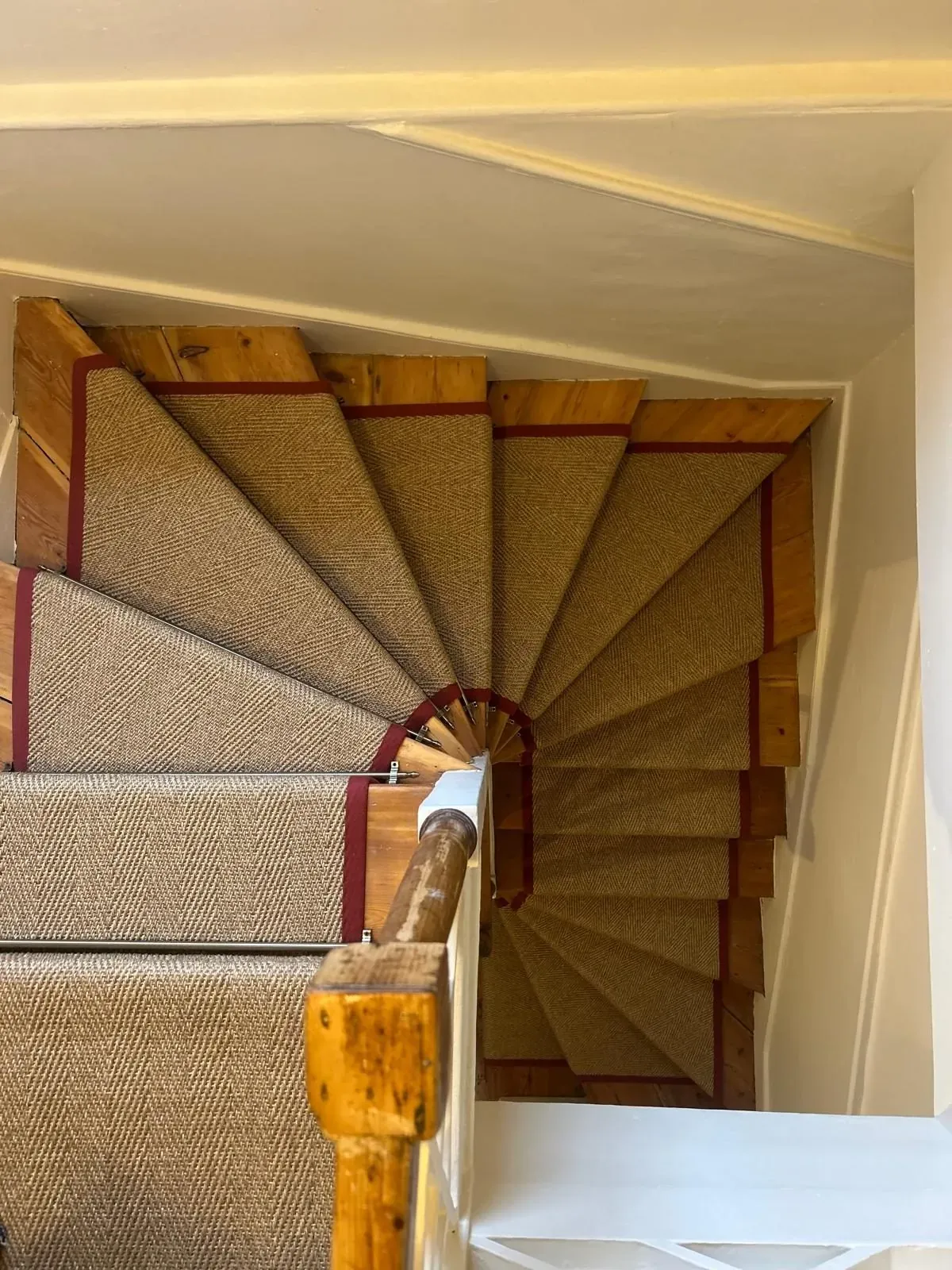 Sisal-look stair runner with red border fitted on a spiral winder staircase