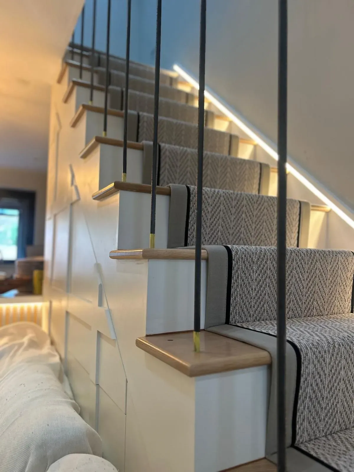 Herringbone runner on a modern open staircase with LED handrail lighting