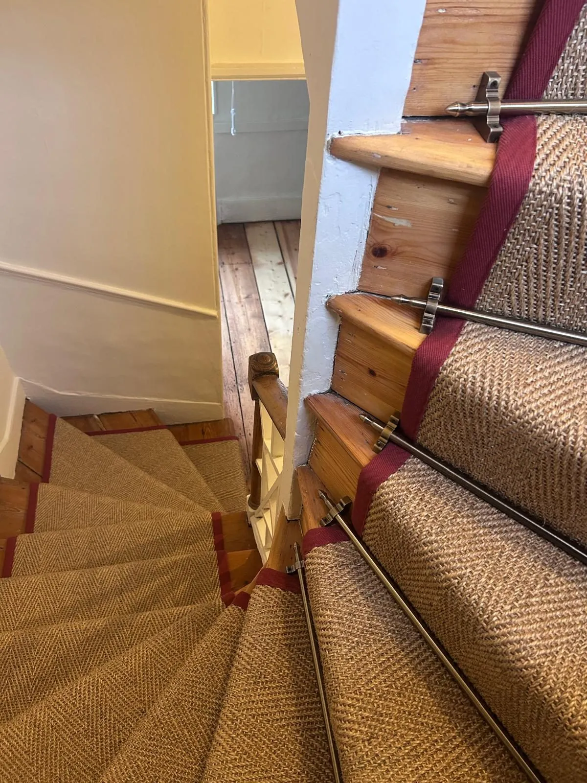 Sisal stair runner with red border on a winding staircase, fitted by Urban Floors in Islington
